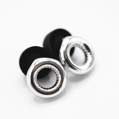 זוג אטמי אוזניים למוזיקאים AudioFeel, בעלי עיצוב מודרני עם חלק מתכתי כסוף מבריק בצורת טבעת פתוחה וקצה פנימי שחור מגומי, המונחים בזווית על רקע לבן.